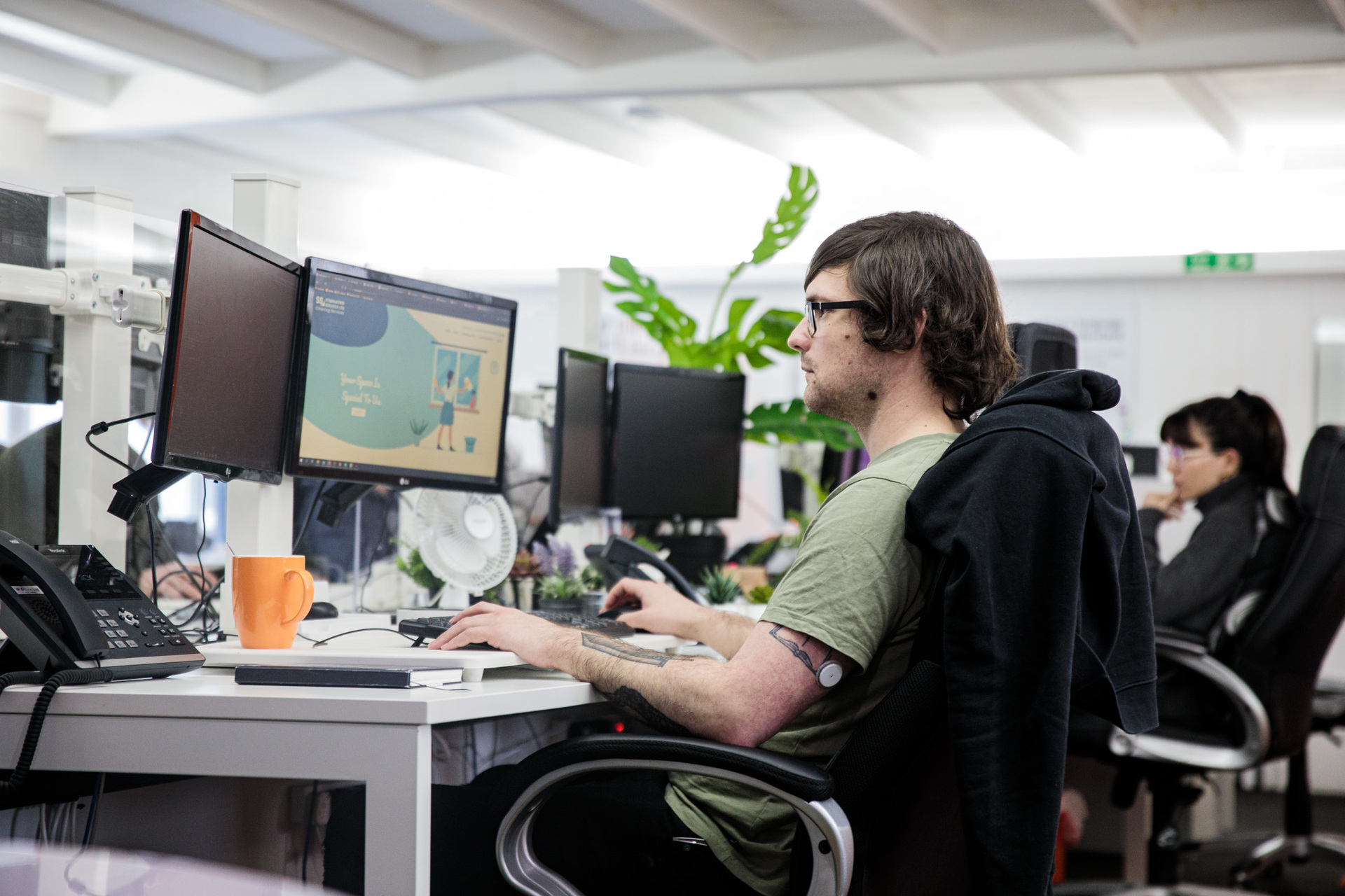 A website designer sat at his desk working on a computer